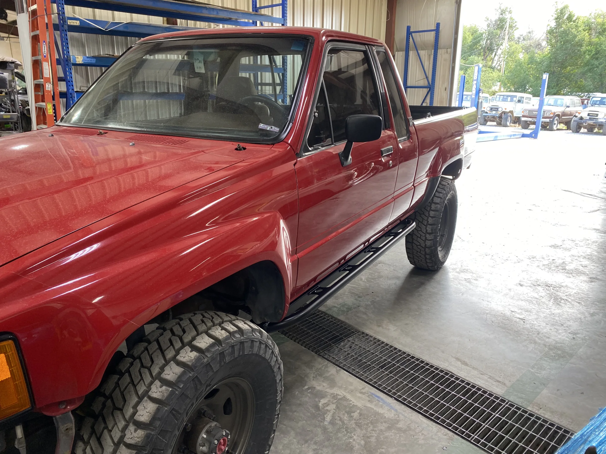 Custom rock sliders installed on the red 1985 Toyota Pickup