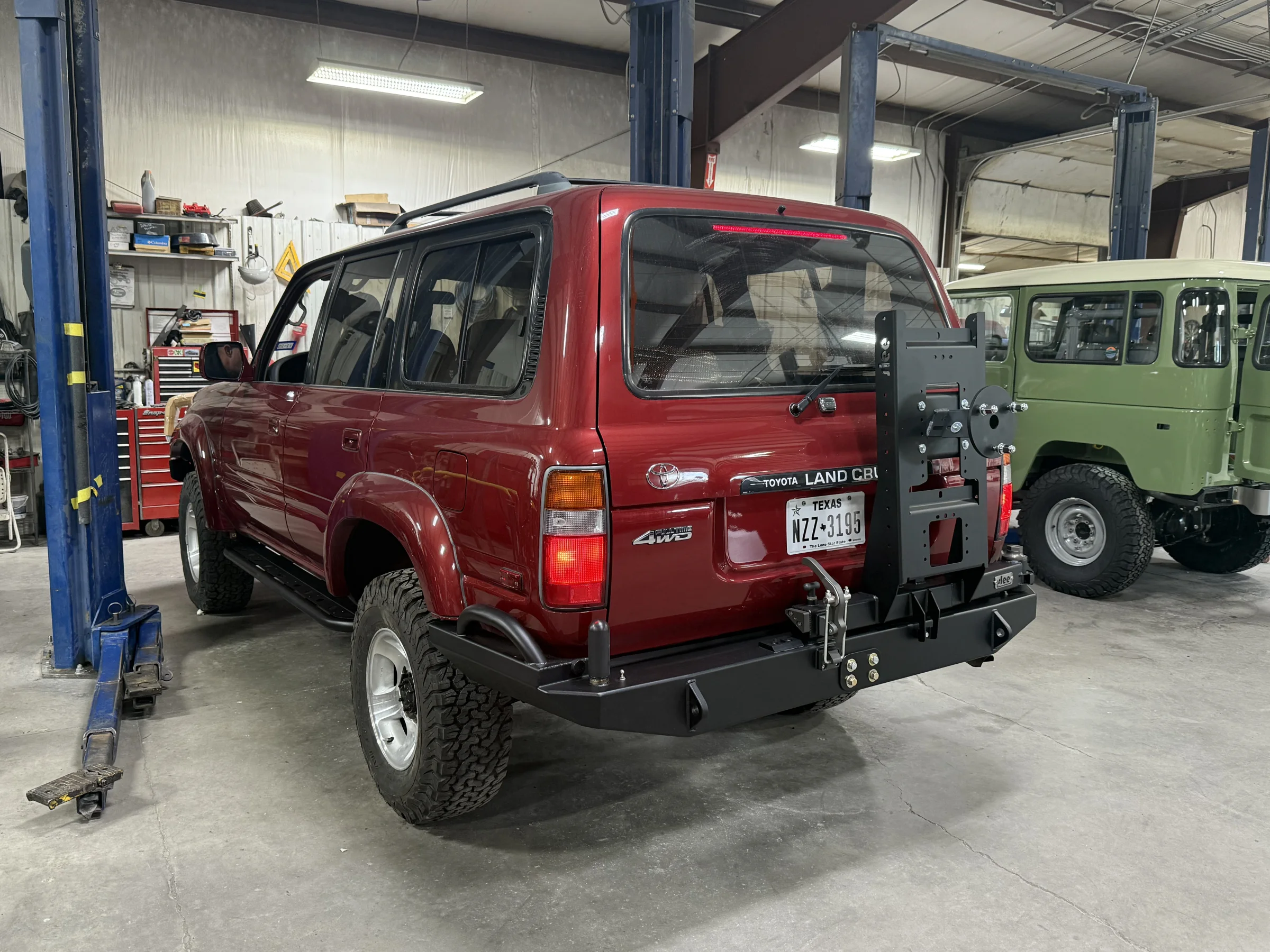 Rear three-quarter view of the red 80 Series Land Cruiser with its Slee rear bumper and tire carrier