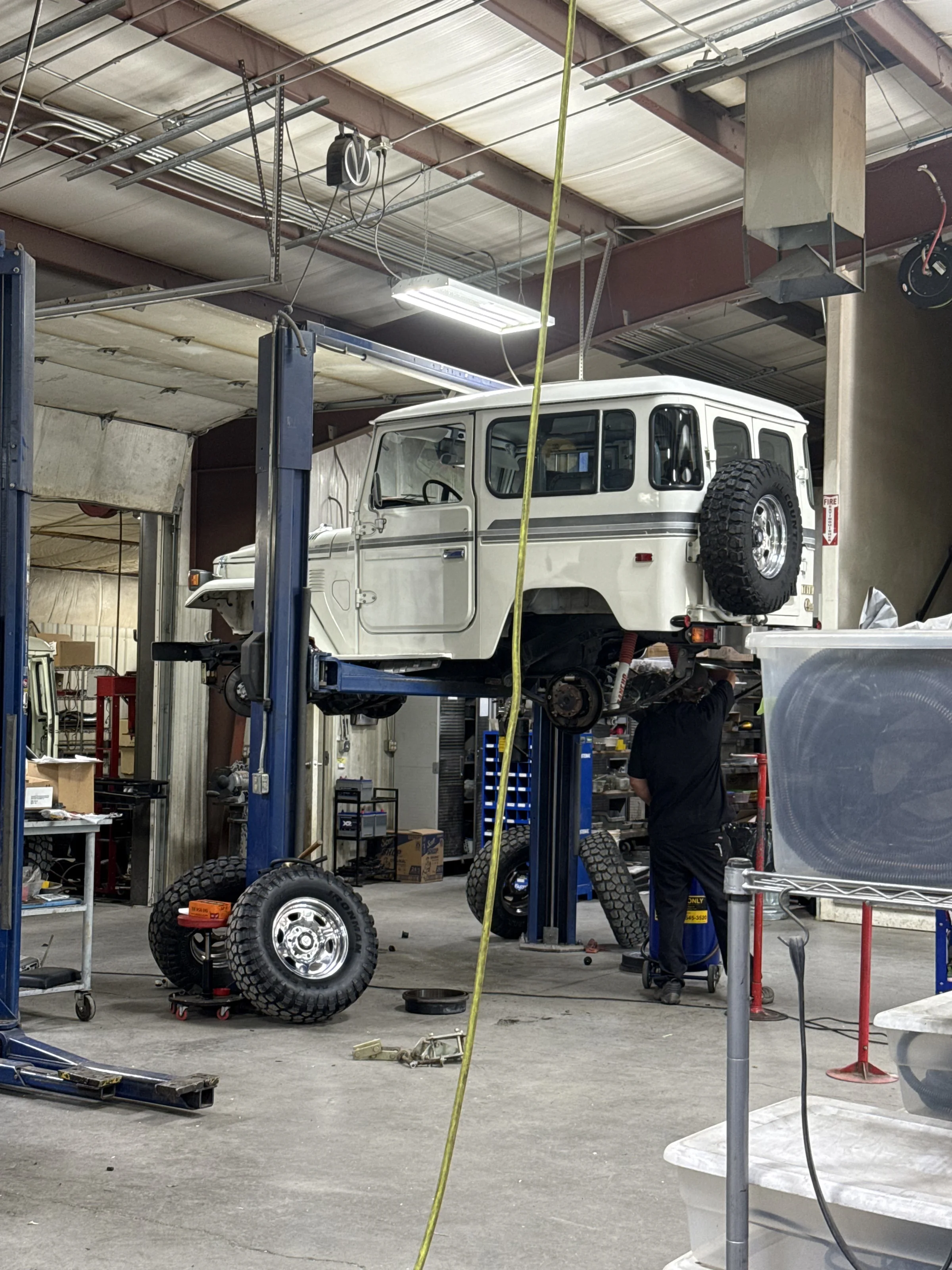 White 1983 Toyota FJ40 raised on a shop lift during preservation work