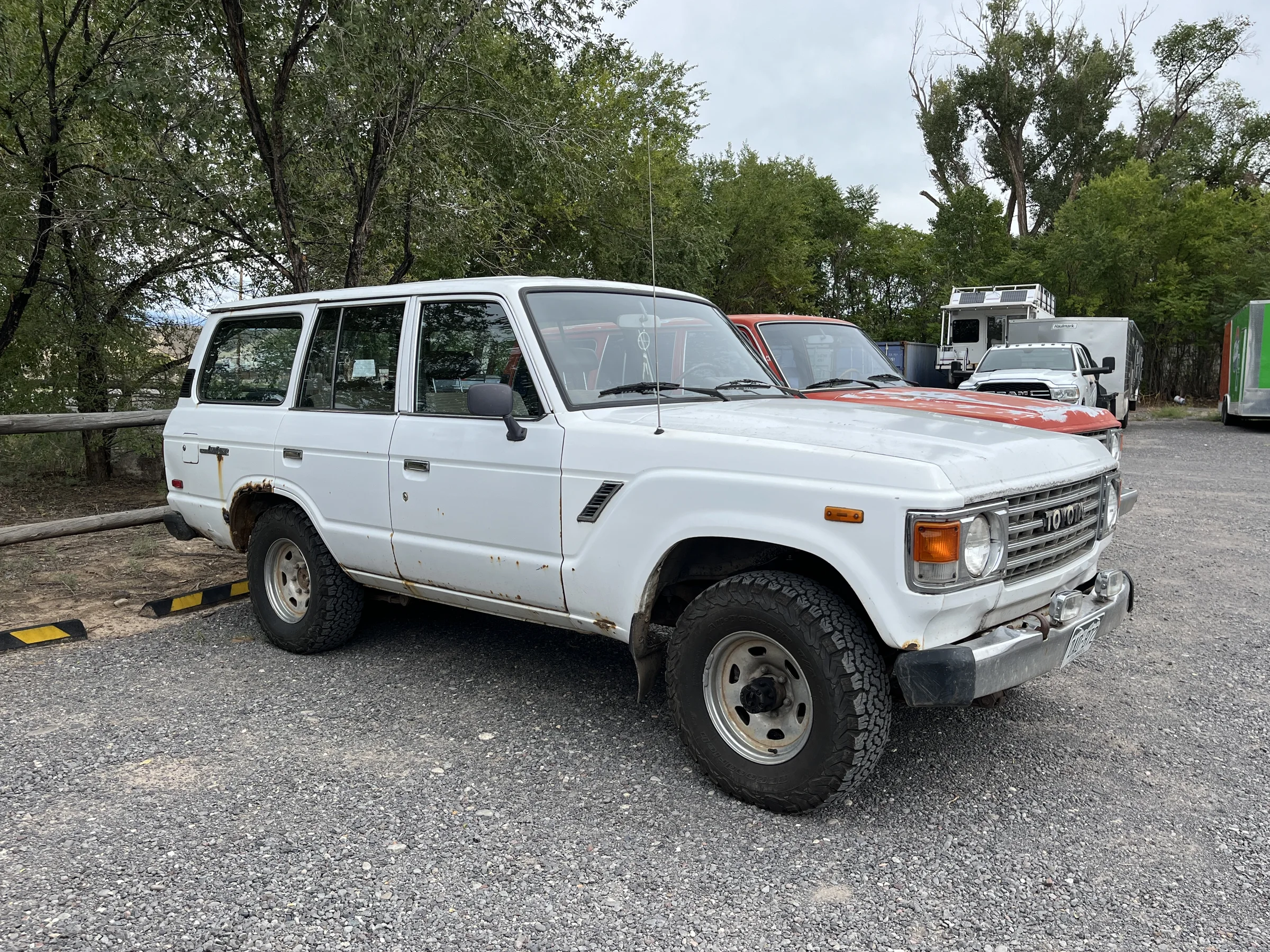 Well-loved white 1981 Toyota FJ60 with the red FJ60 behind it