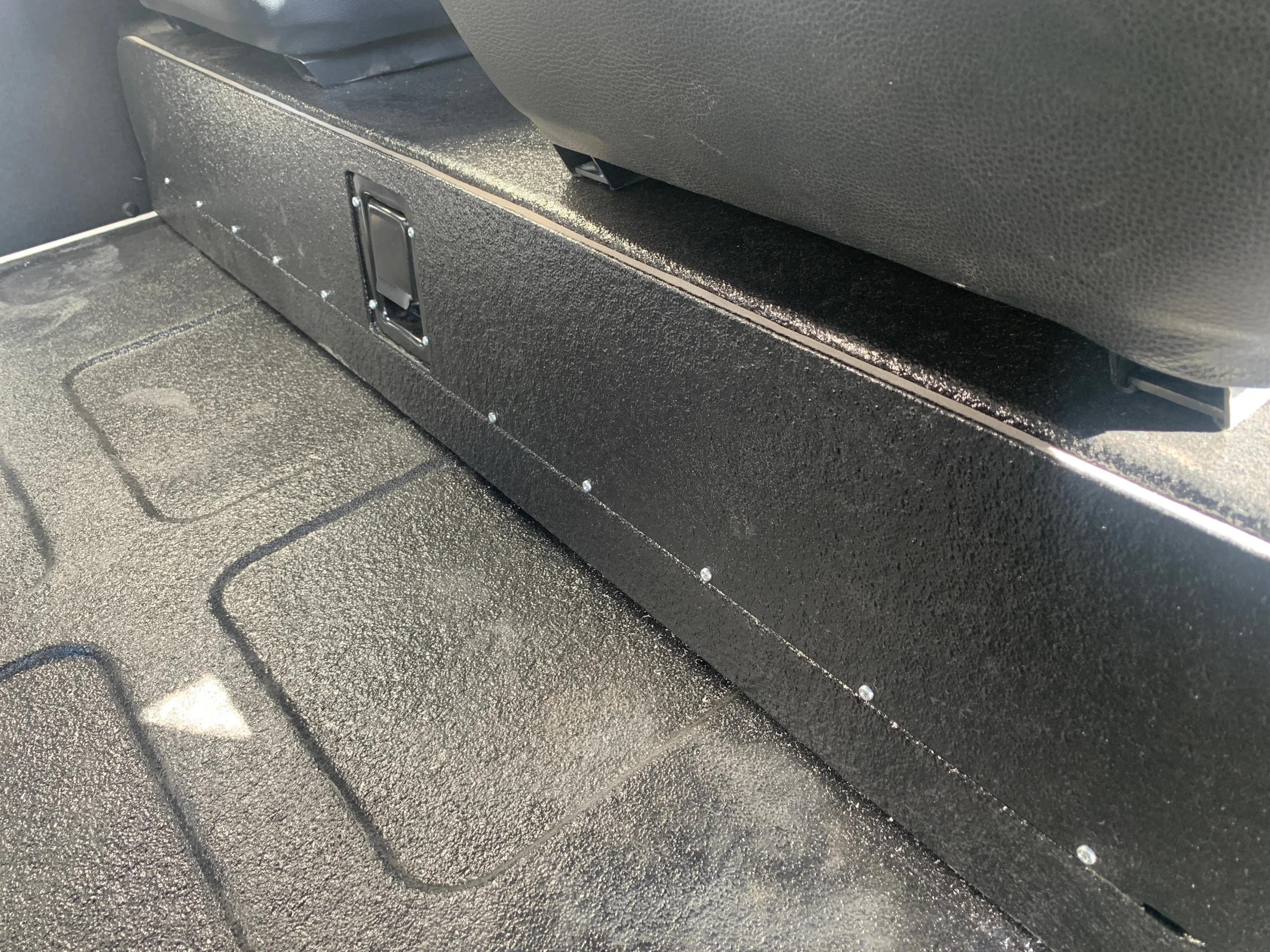 Custom black under-seat storage compartment fabricated for a classic Mercedes G Wagon