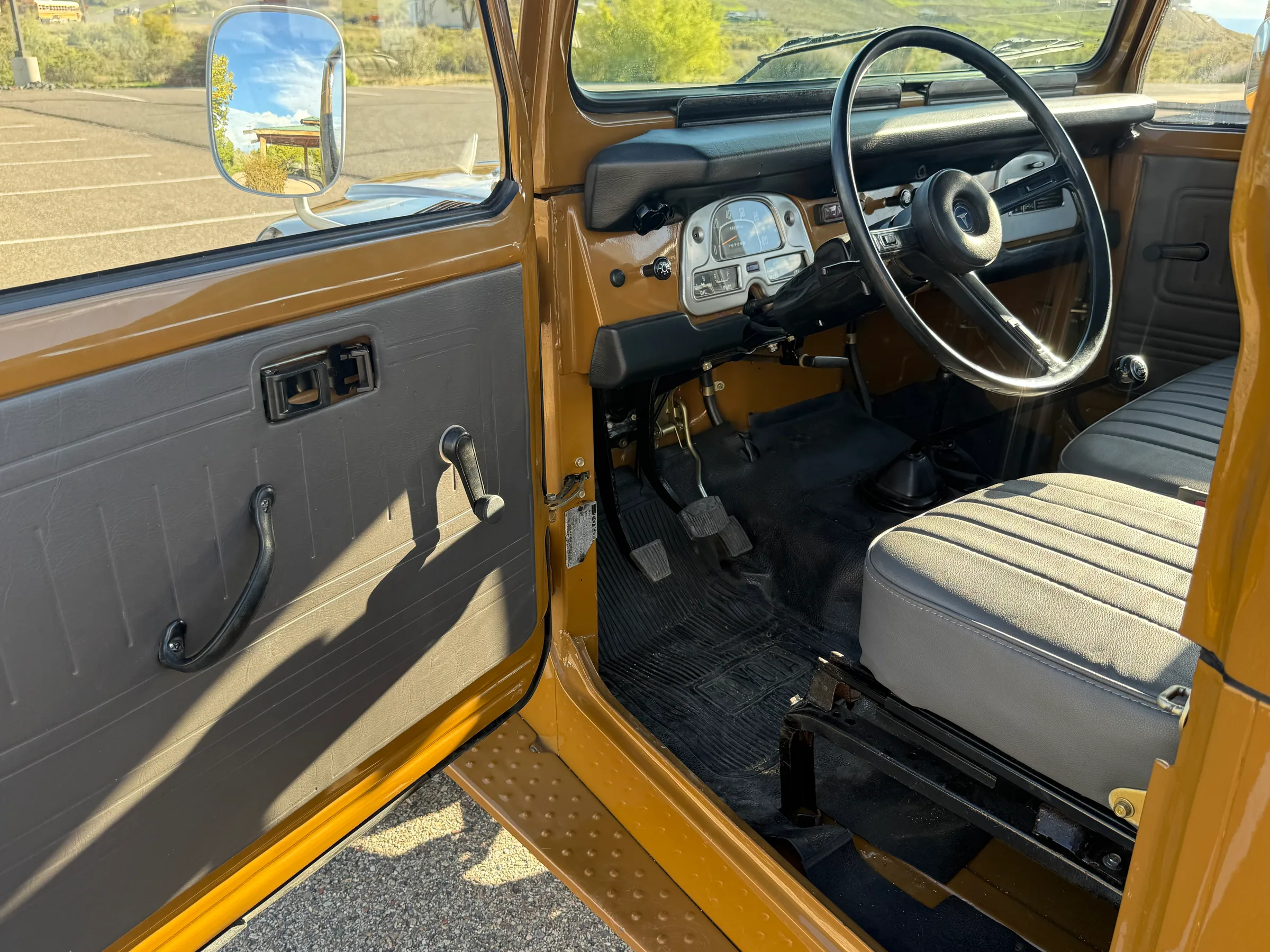 Driver-side cabin, steering wheel, and front bench seat in the FJ45