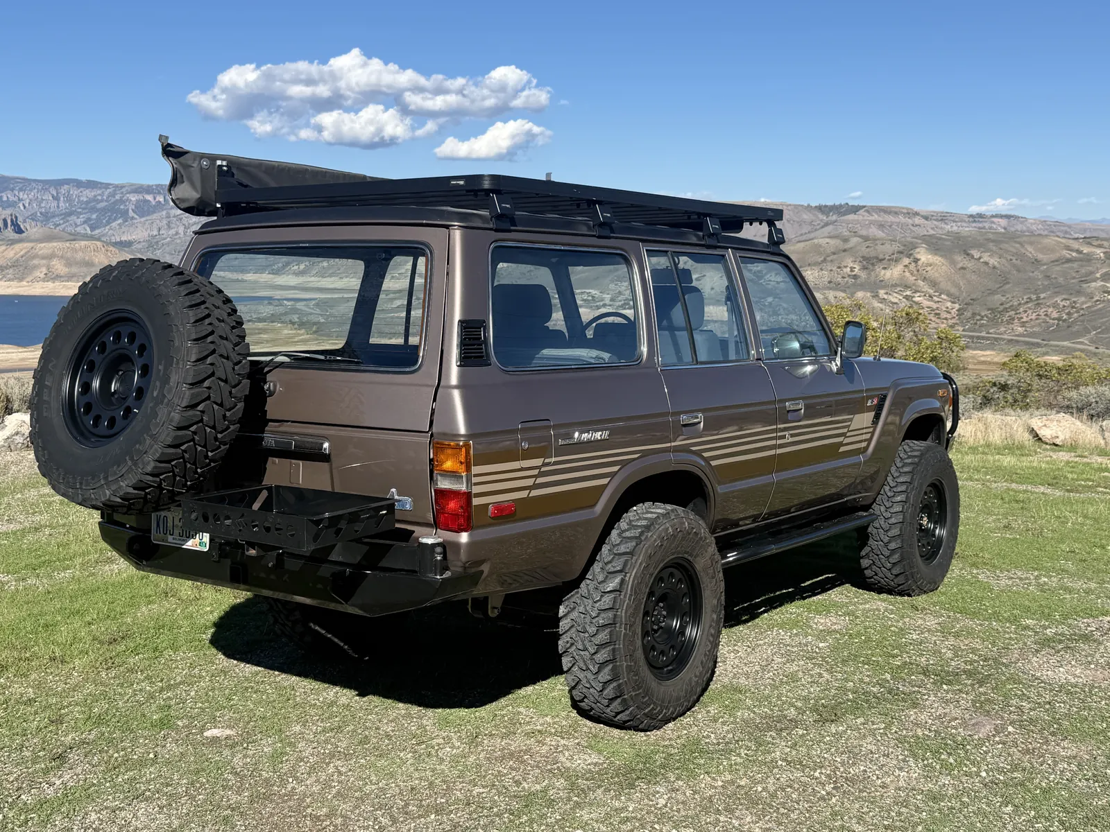 Rear driver-side view of the FJ60 with awning and spare tire carrier