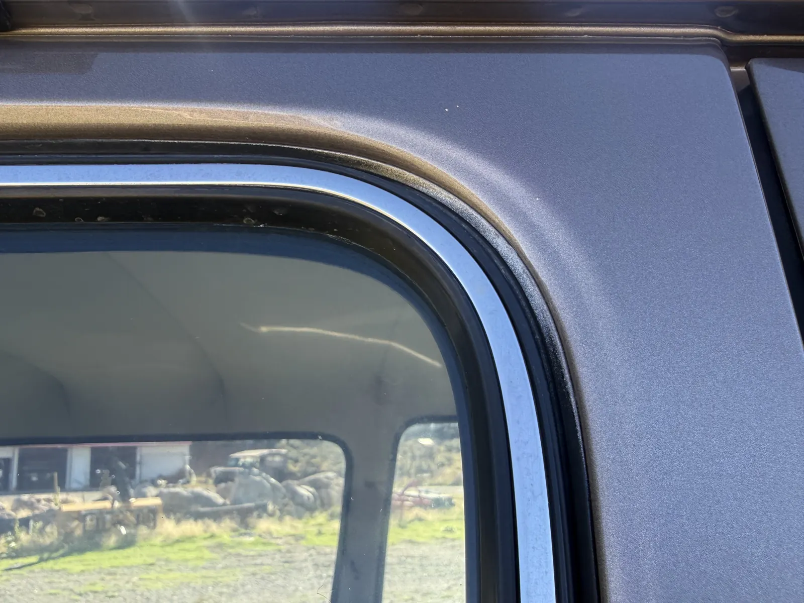 Paint and weatherstripping detail around a rear side window