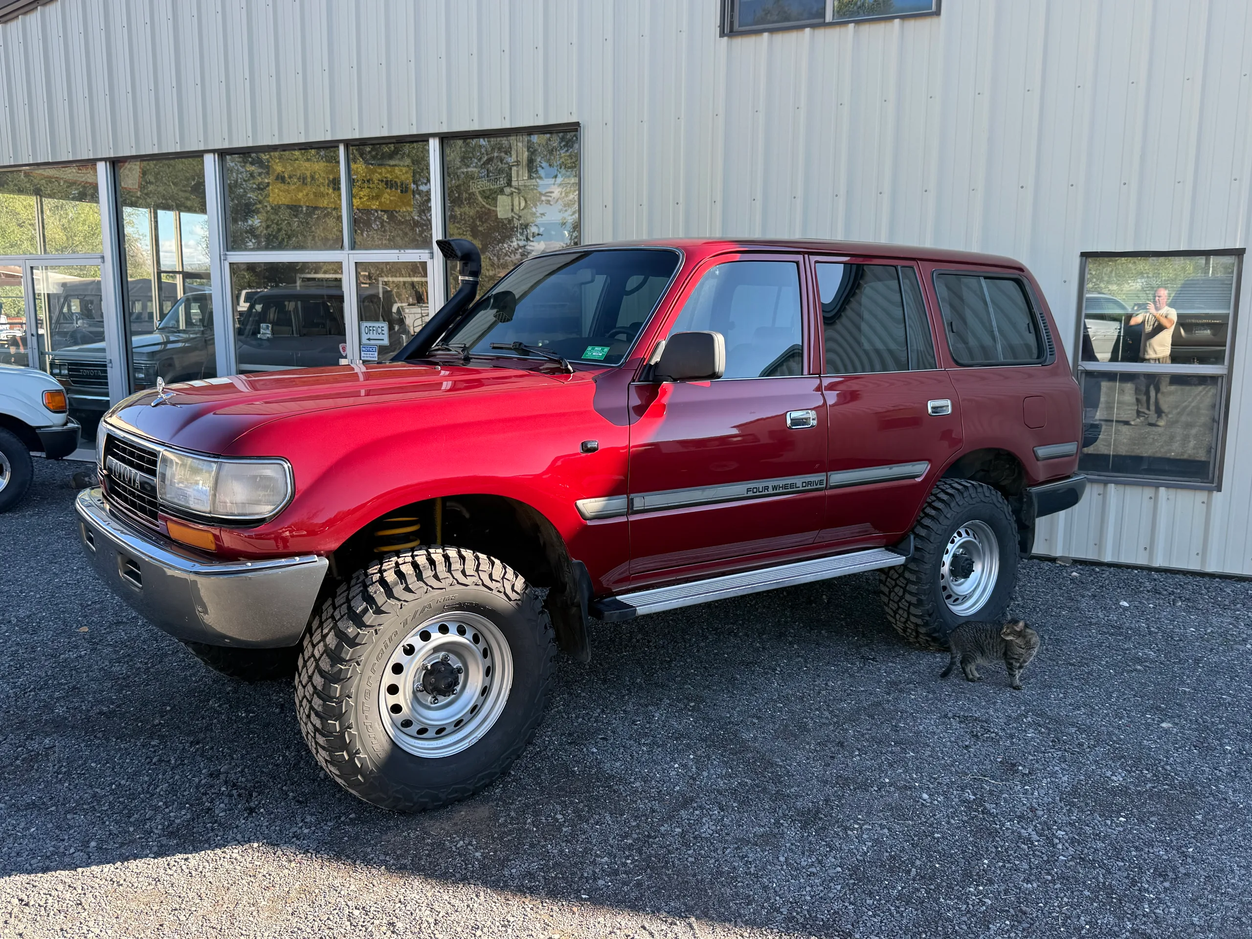 Front driver-side view of the red 1990 Toyota Land Cruiser FJ80