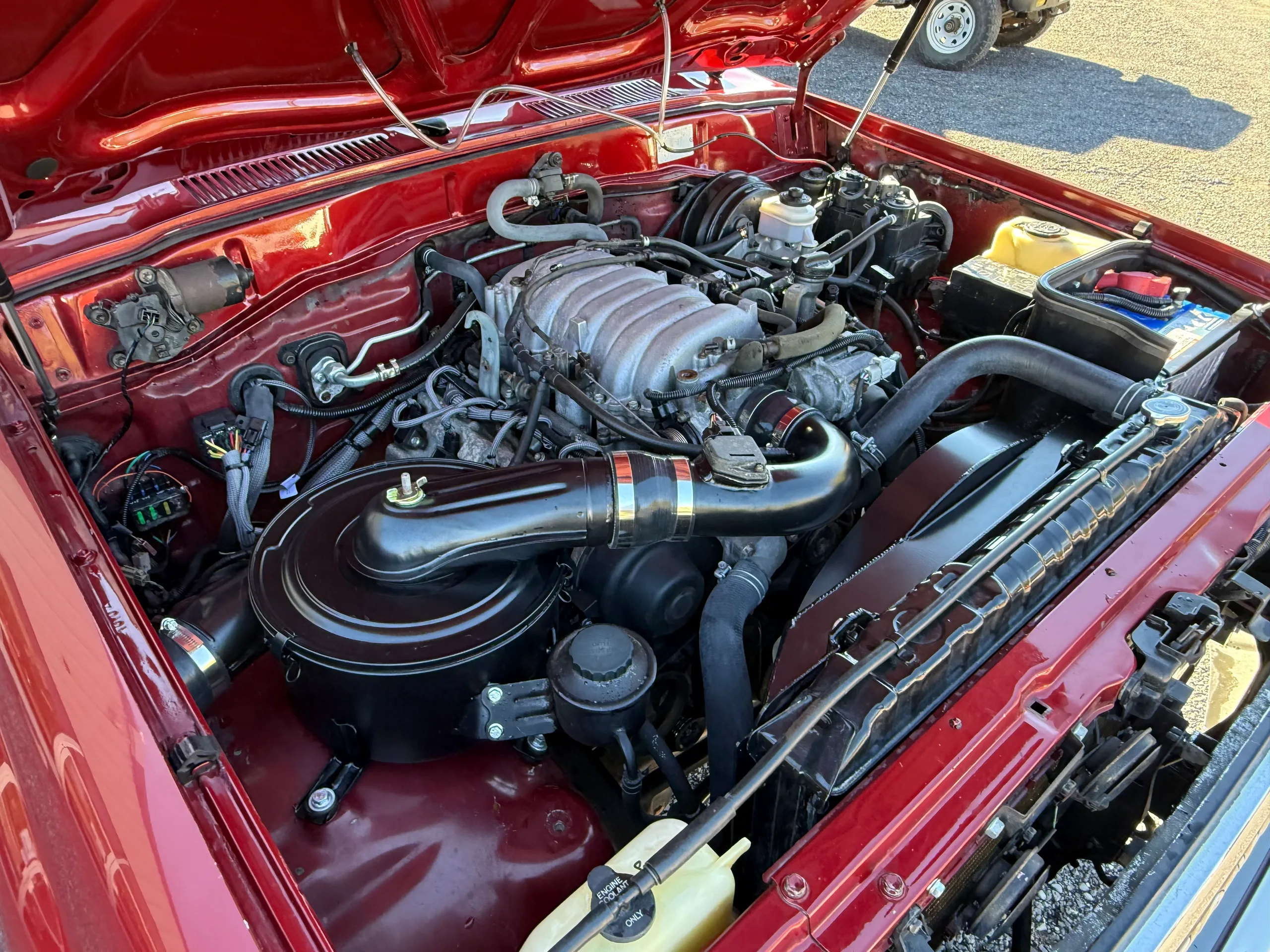 Complete 2UZ V8 engine bay in the red Toyota Land Cruiser FJ80