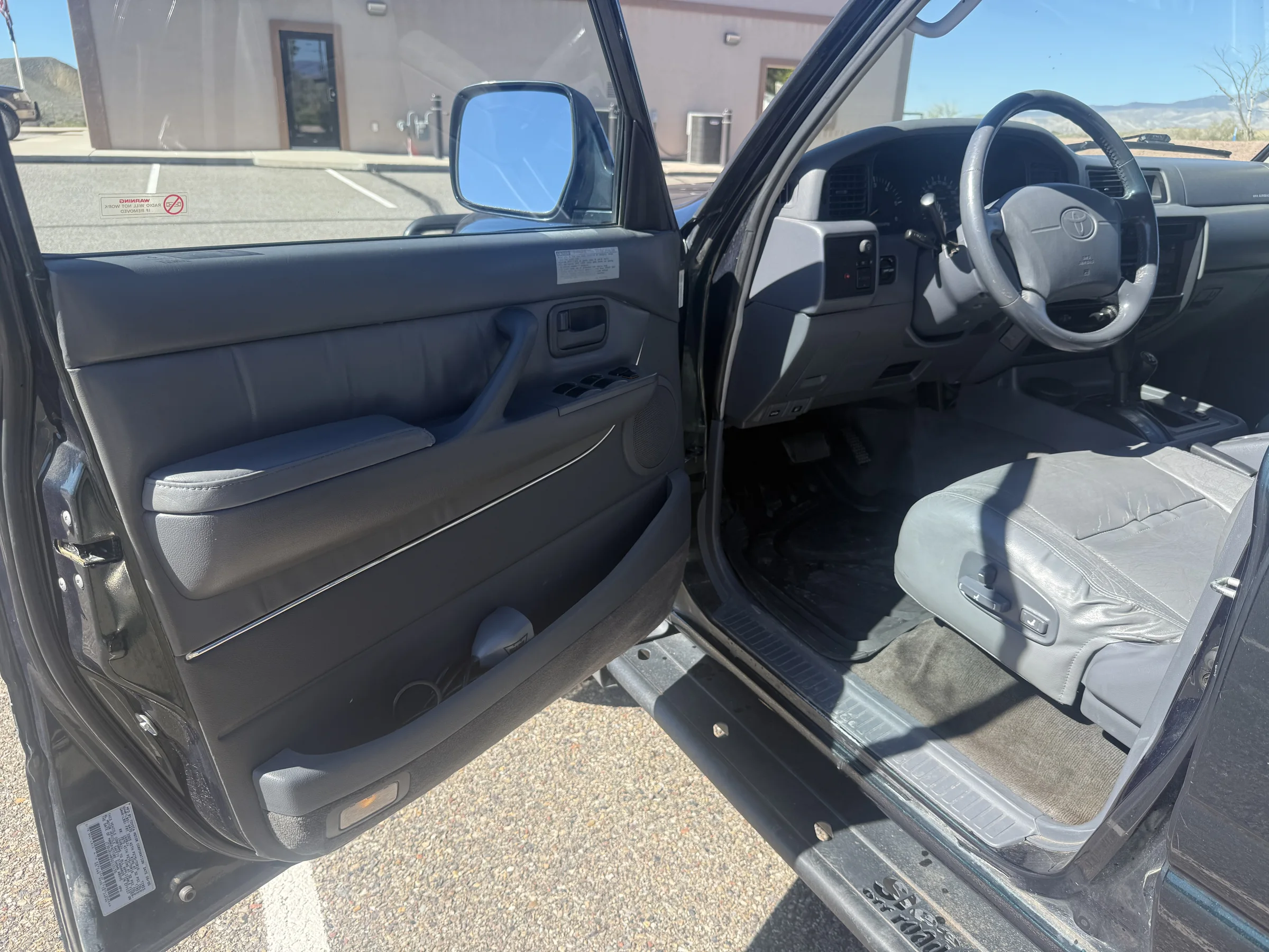Open driver door and front cabin interior in the 1996 FZJ80